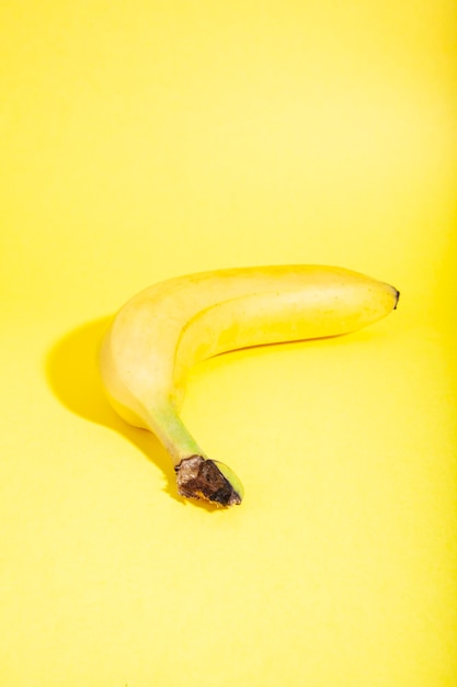 Banana madura inteira com pele isolada em fundo amarelo