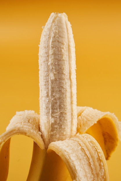 Banana meio descascada inteira isolada em amarelo
