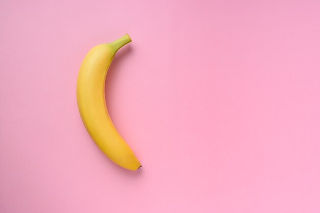 Banana na superfície rosa.