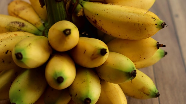 bananas amarelas maduras agrupadas em um fundo de madeira. Frutos pequenos de banana.