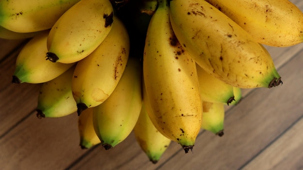 bananas amarelas maduras agrupadas em um fundo de madeira. Frutos pequenos de banana.