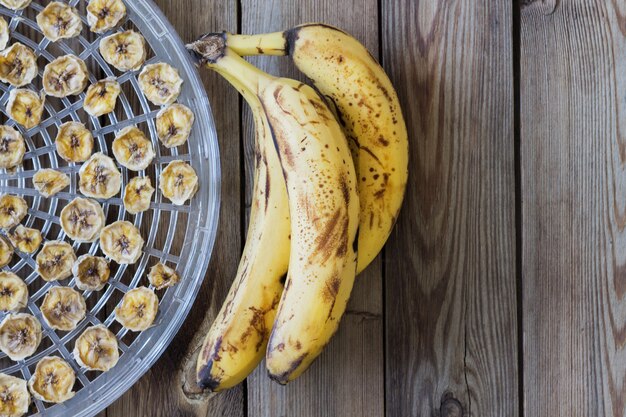 Bananas e lascas de banana na mesa de madeira na orientação horizontal. Fruta orgânica feia na moda.