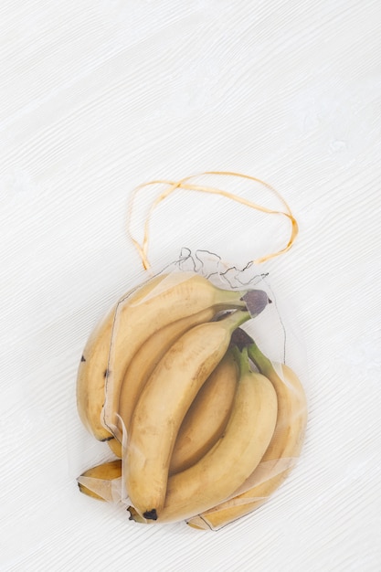 Foto bananas frescas amarelas em sacos ecológicos naturais costurando de tecido de malha