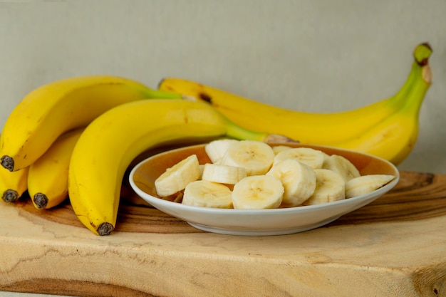 Bananas frescas e bananas cortadas em pedaços em uma tigela sobre a mesa foto de stock