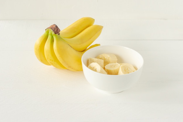 Bananas maduras cortadas em uma tigela branca para comer. Lanche saudável ou conceito de café da manhã.