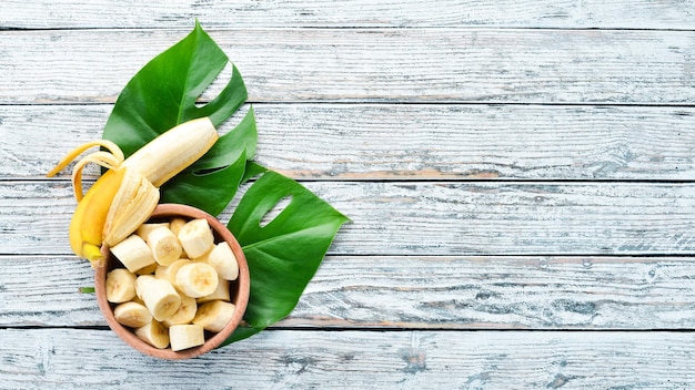 Banane mit grünen Blättern auf einem weißen Holztisch Tropische Früchte Draufsicht Kostenloser Kopierbereich