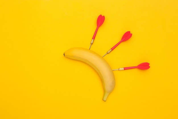 Banane mit Pfeilen auf gelbem Hintergrund.