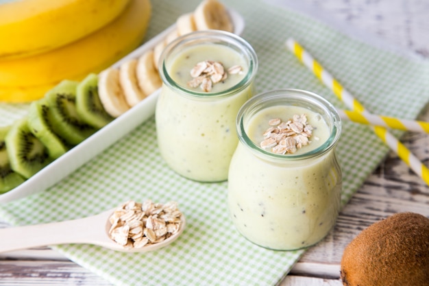 Banane Smoothie mit Kiwi und Hafer auf einem hellen Holztisch. Protein-Diät. Gesundes Nahrungsmittelkonzept.