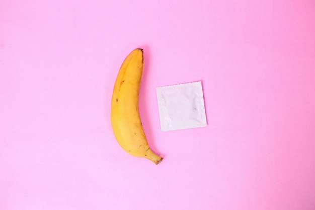 Banane und Verhütung isoliert auf rosa Hintergrund