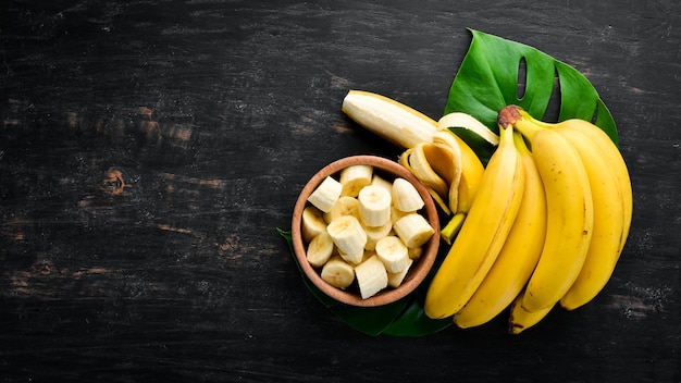 Bananen auf einer schwarzen Holzoberfläche Tropische Früchte Draufsicht Kostenloser Kopierbereich