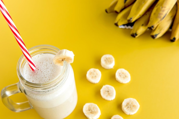 Bananen-Smoothie-Cup gesunder Shake mit Bananenscheiben im Hintergrund