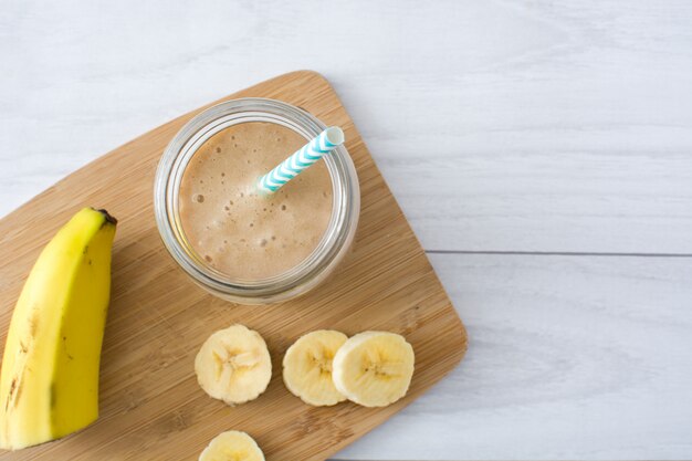 Bananen-smoothies im glas auf weißer hölzerner tischoberansicht