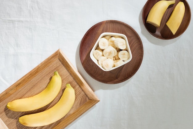Bananen und Bananenstücke auf einem Holzteller