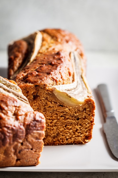 Bananenbrot auf einem grauen Teller, vertikales Foto. Gesundes Dessertkonzept.