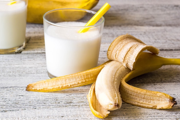 Bananencocktail und frische Bananen auf Holztisch.