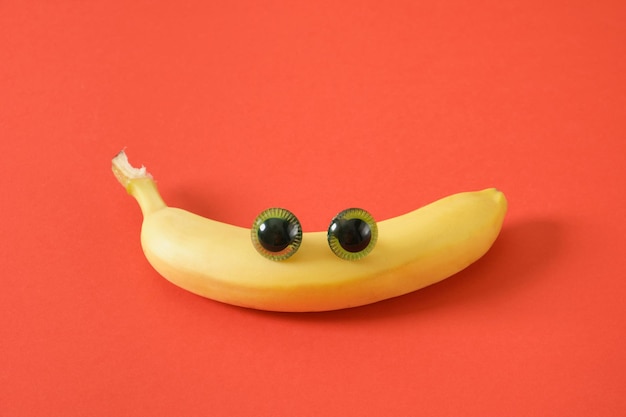 Bananengesicht mit Augen fröhliches Gesicht aus Plastikpuppenaugen und frischer gelber Banane