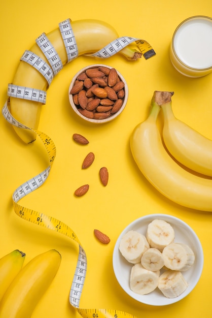 Bananenglas Milch und Mandeln mit Maßband auf gelbem Hintergrund mit Kopierraum