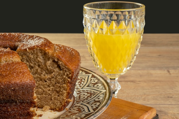 Bananenkuchen und Orangensaft auf Holztisch.