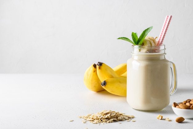 Bananenmilchshake im Einmachglas auf weißer Tafel. Vertikales Format