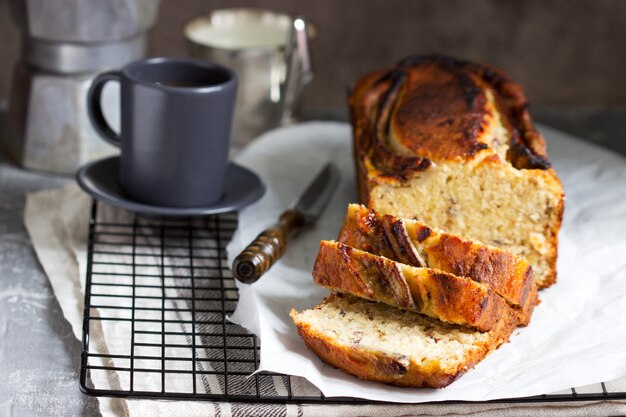 Bananenmuffin mit kandiertem Ingwer und Rosinen und Getränken auf grauem Hintergrund.