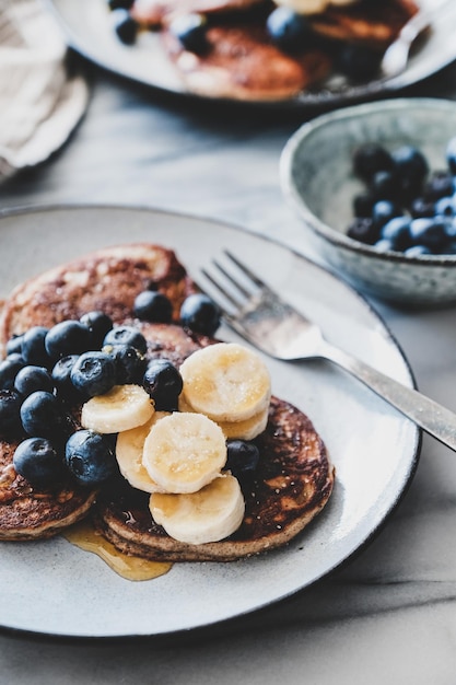 Bananenpfannkuchen mit Heidelbeere und Honig über Marmortisch