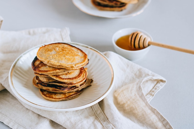 Bananenpfannkuchen mit Honig, Honigschöpflöffel auf einem weißen Hintergrund