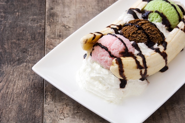 Foto bananensplit-eisdessert mit schokoladensirup auf holz