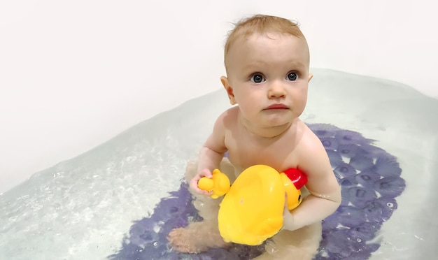 Bañar a un bebé en una bañera con agua limpia niña jugando con patosxA