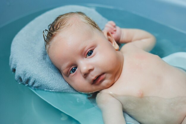 Bañar a un bebé en un baño de bebé El primer baño de un bebé recién nacido Un bebé se baña en un baño con agua Higiene personal de un recién nacido