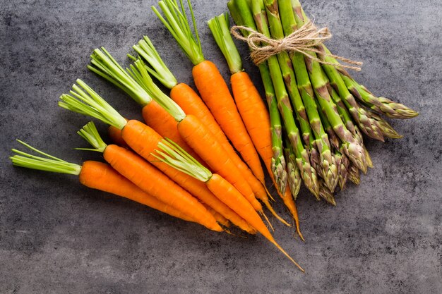 Banches von frischem grünem Spargel und Gemüse auf Holzoberfläche, Draufsicht