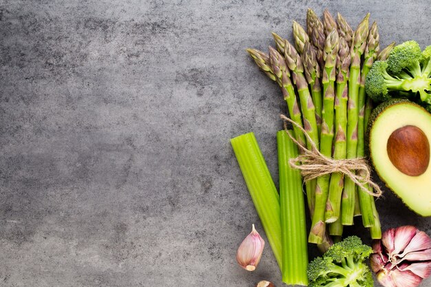 Banches von frischem grünem Spargel und Gemüse auf Holztisch, Draufsicht