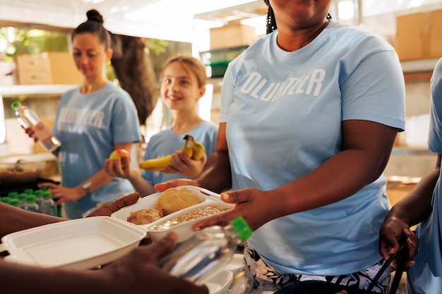 En un banco de alimentos sin fines de lucro, una mujer afroamericana sirve frijoles horneados a los menos afortunados.