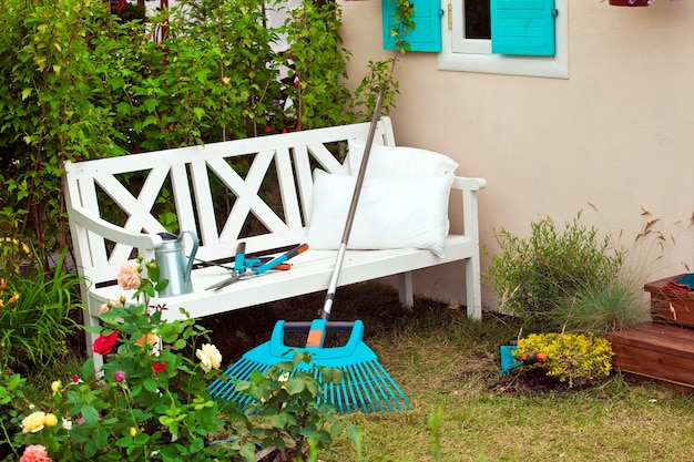 Banco branco no quintal com instrumentos de jardinagem