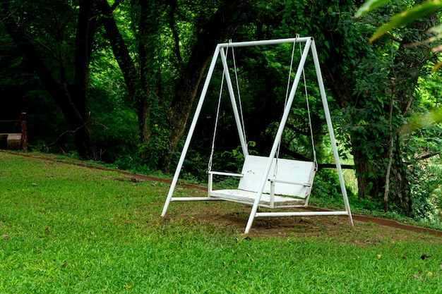 Banco de columpio blanco bajo un árbol verde