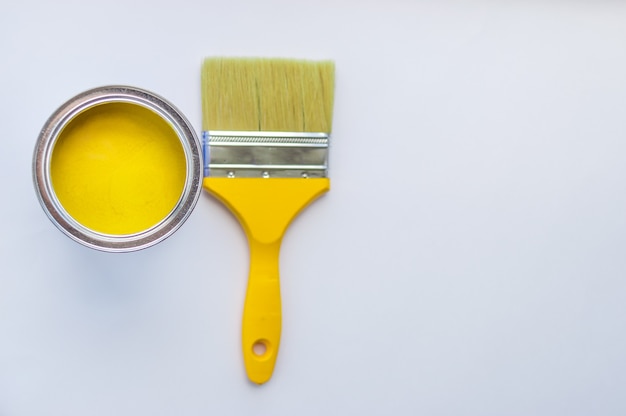 Banco com tinta amarela e pincel amarelo em fundo branco