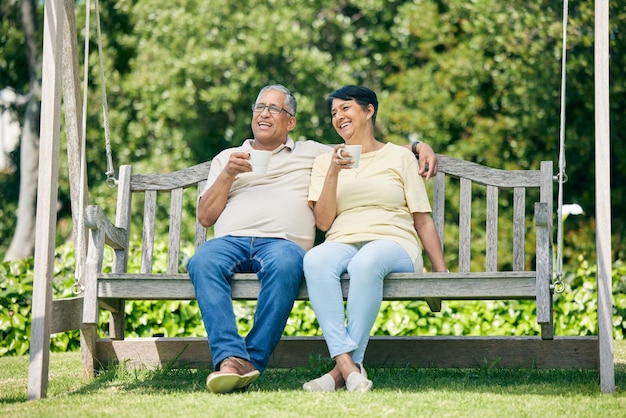 Banco de data de café ou casal de velhos no parque ou na natureza conversando e se unindo na aposentadoria Homem idoso sênior ou mulher madura feliz bebendo chá para relaxar com amor, paz ou cuidado em férias divertidas