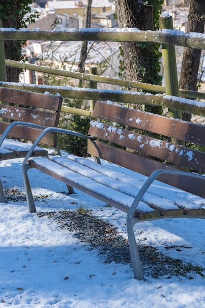 banco de madera nevado em um parque