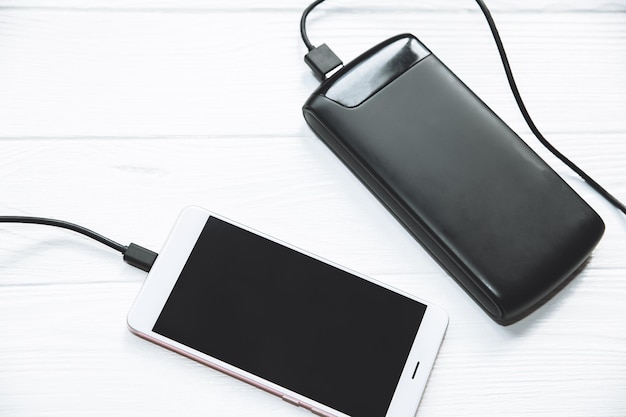 Foto banco de potência preto com usb e smartphone em fundo de madeira foto moderna da tecnologia da informação