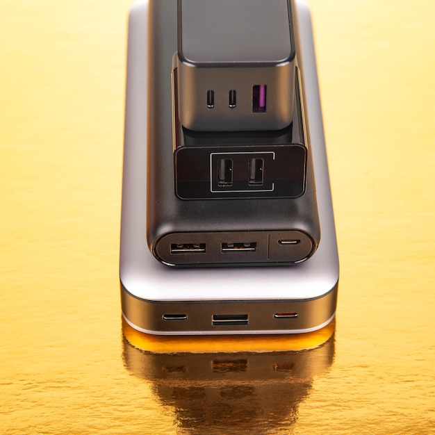 Foto banco de energía y enchufe de carga sobre un fondo dorado dispositivos electrónicos para cargar dispositivos