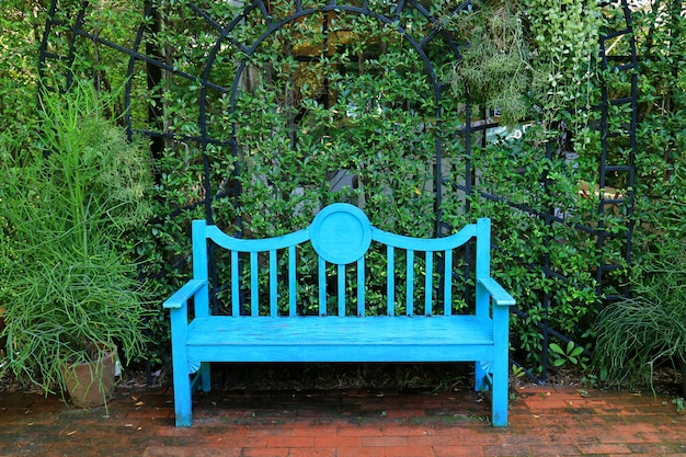 Banco de madera de color azul turquesa vivo en el camino de ladrillos de terracota en jardín verde