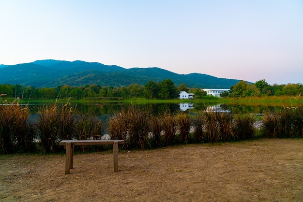 Foto banco de madera con hermoso lago en chiang mai con montañas boscosas y cielo crepuscular en tailandia.