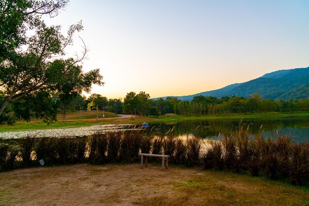 Banco de madera con hermoso lago en Chiang Mai con montañas boscosas y cielo crepuscular en Tailandia.