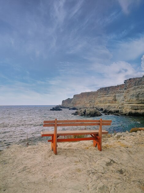 Banco de madera sobre un acantilado de piedra sobre el mar