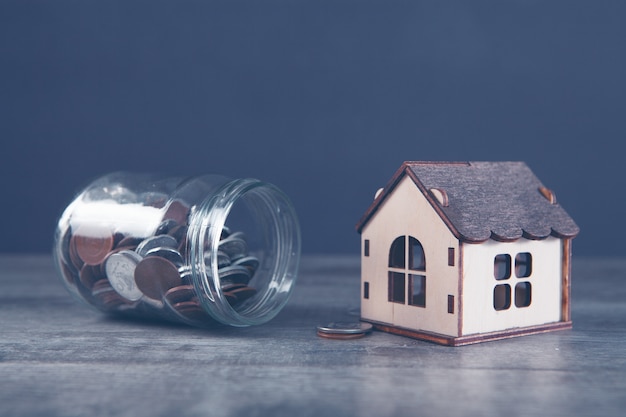 Un banco con monedas y una casa sobre la mesa.