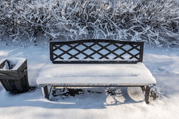 Un banco en un parque de la ciudad cubierto con las primeras nevadas Paisaje de la ciudad de invierno