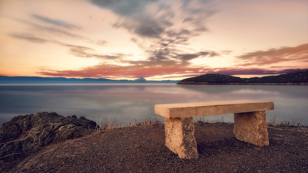 Banco de piedra al atardecer Hermosa puesta de sol sobre la península del mar Egeo Kassandra Halkidiki Grecia