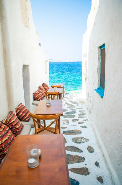 Bancos com almofadas em um típico café grego ao ar livre em Mykonos com uma vista incrível do mar nas ilhas Cíclades