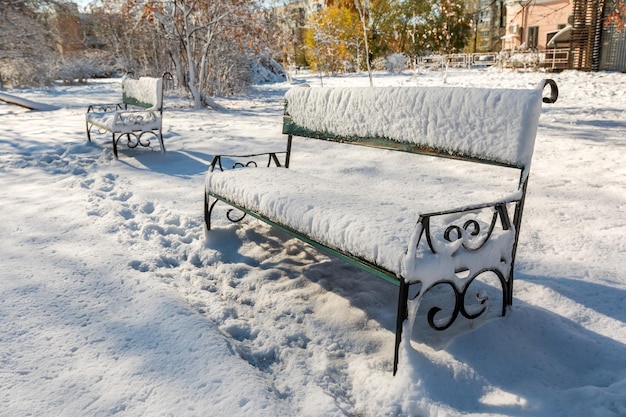 Bancos cubiertos de nieve después de una nevada en un parque de la ciudad. Patrones de la ciudad de invierno.