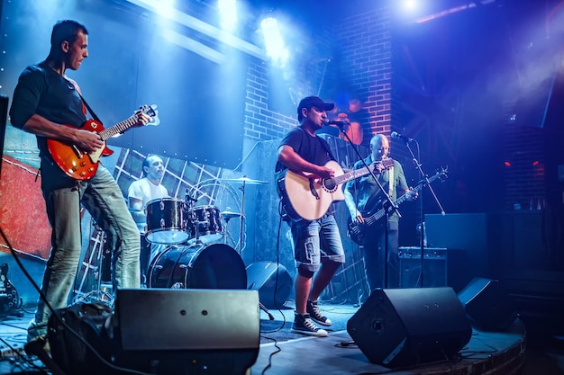 La banda actúa en el escenario, concierto de música rock. Advertencia: disparos auténticos con iso alto en condiciones de iluminación difíciles. Un poco de grano y efectos de movimiento borrosos.