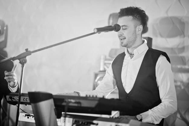 Foto banda ao vivo de música musical tocando em um palco com luzes diferentes teclado tocando